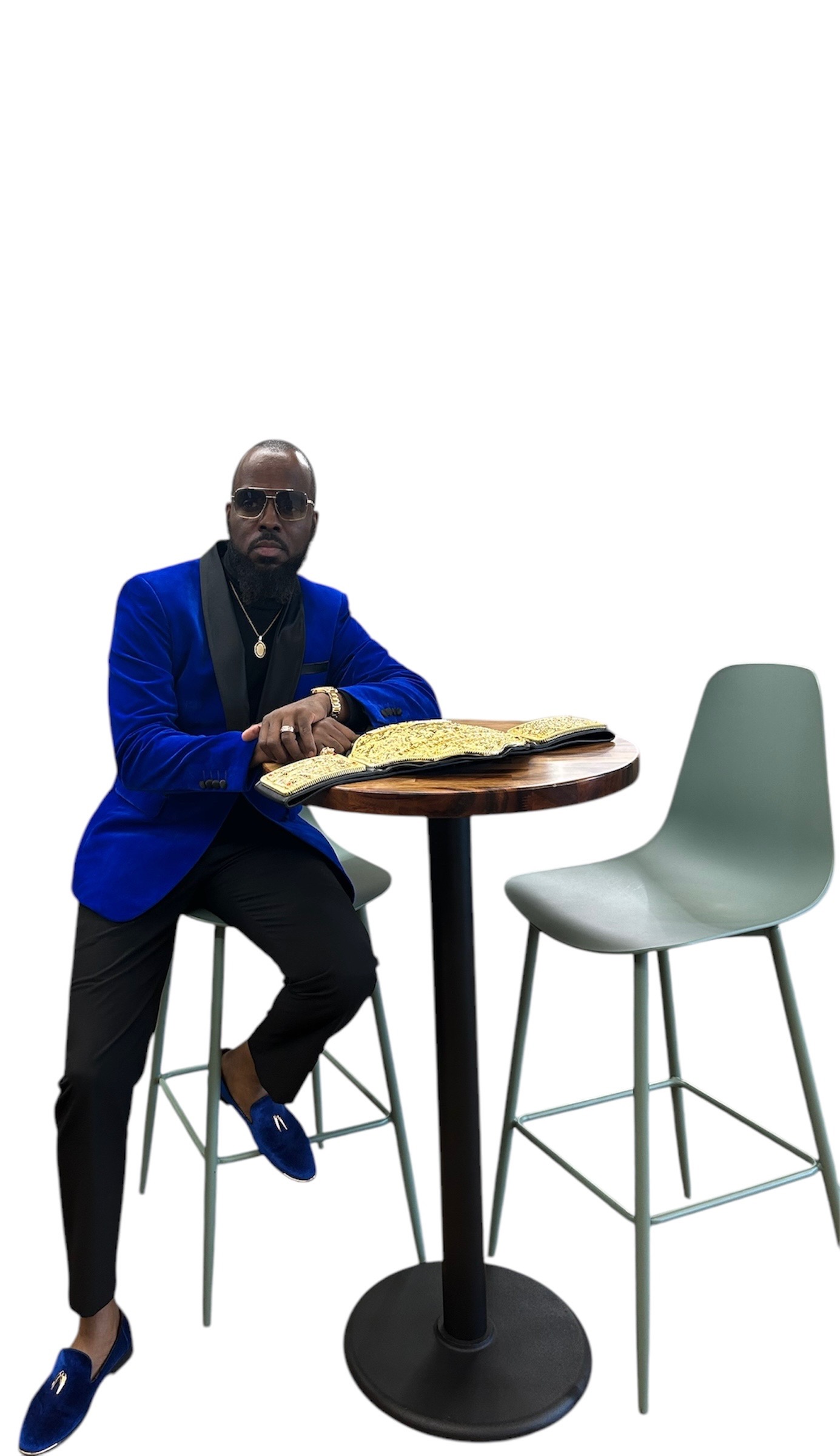 Corey Wims in a blue velvet jacket, seated with a championship belt